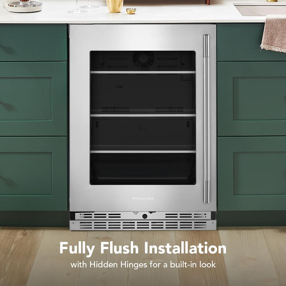 24-inch undercounter refrigerator with glass door, metallic accents, and stainless steel handle in green kitchen cabinetry
