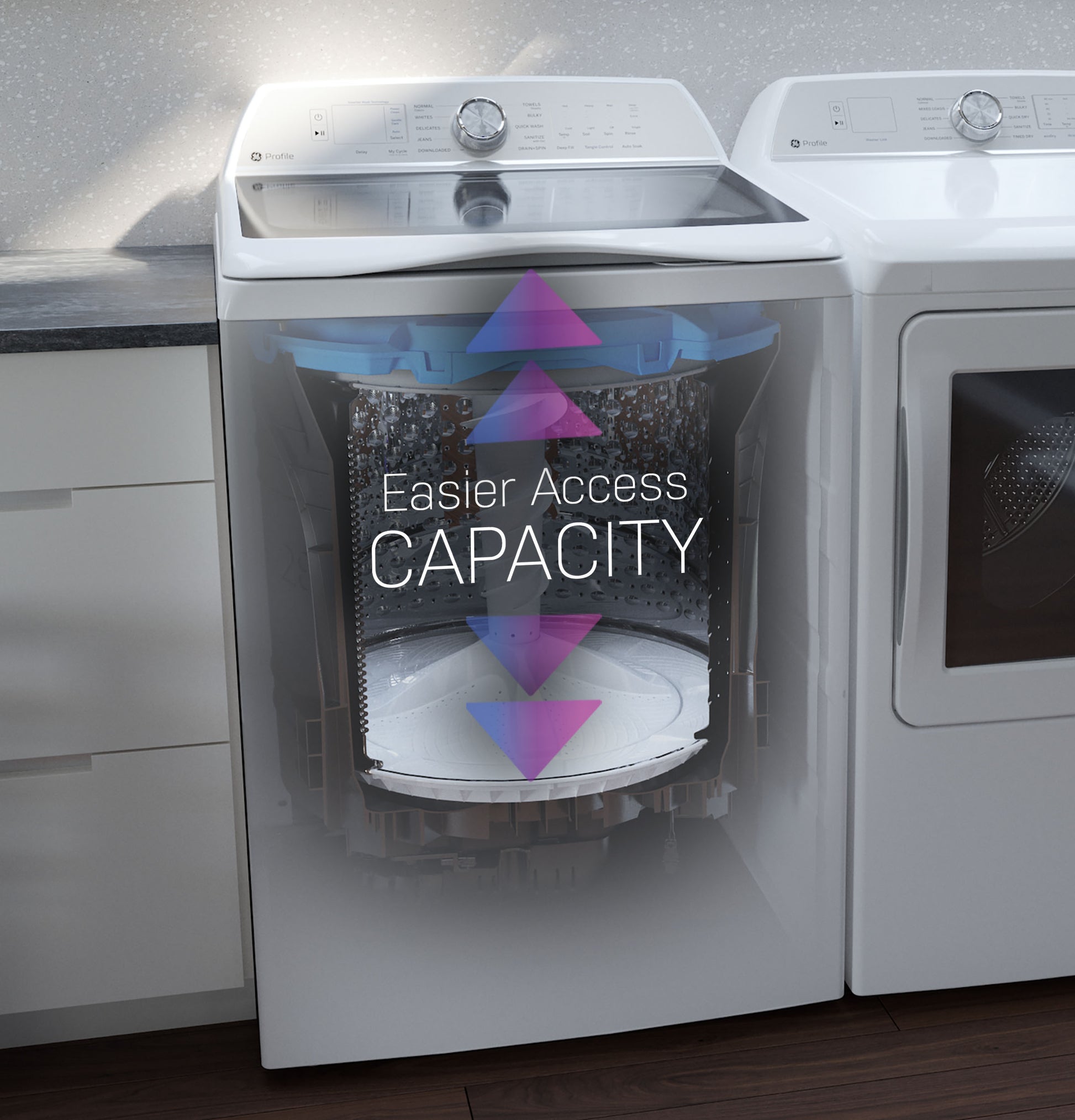 Front view of white top load washer with transparent section showing drum capacity and easier access arrows in laundry room setting