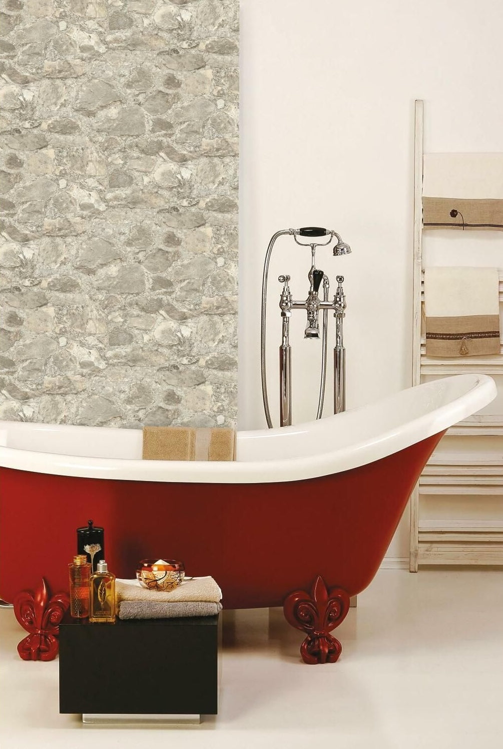Red clawfoot bathtub with chrome faucet next to wall covered in weathered stone peel and stick wallpaper