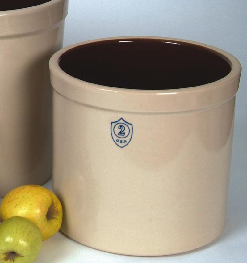 Beige 2-gallon stoneware crock with dark brown glazed interior and blue shield emblem on the front