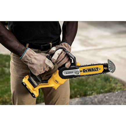 Person wearing gloves holding a yellow cordless pruning chainsaw for tools and home improvement tasks