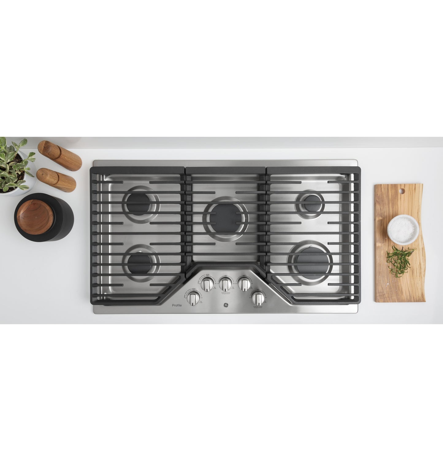 Top view of stainless steel built-in gas cooktop with five burners and control knobs in a kitchen setting