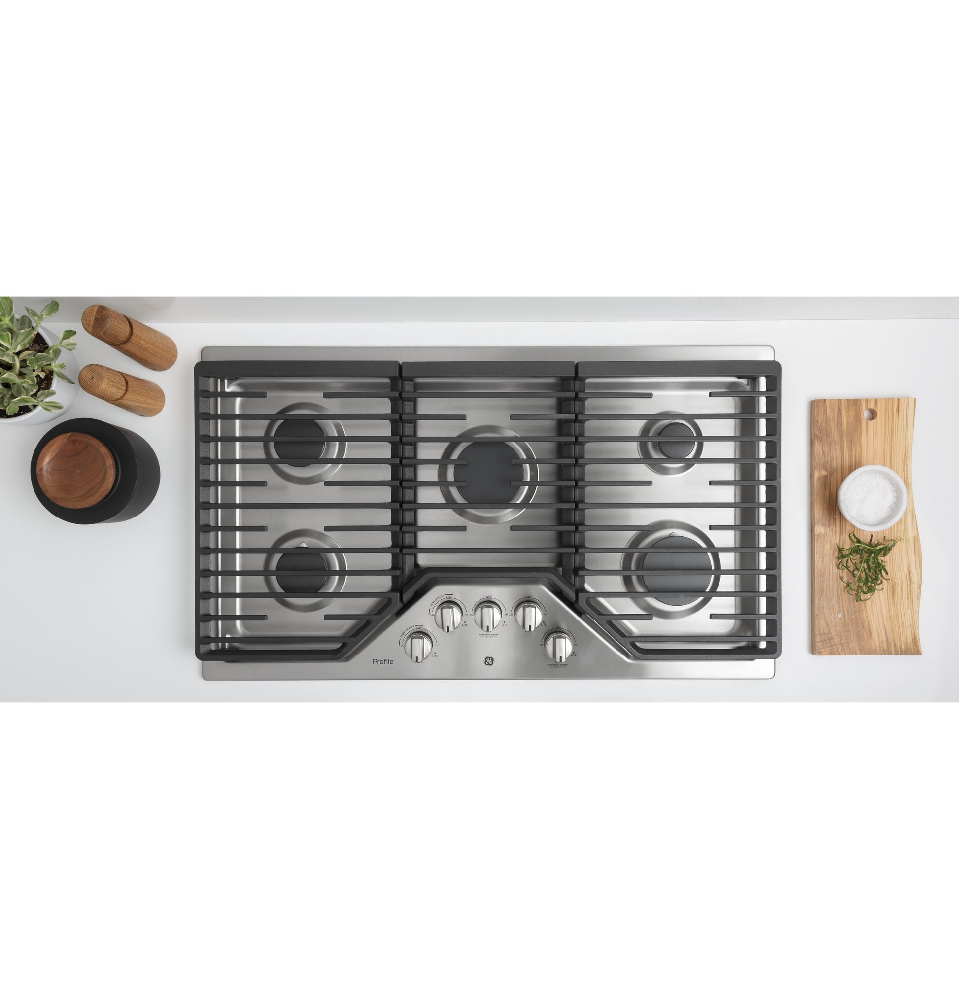 Top view of stainless steel built-in gas cooktop with five burners and control knobs in a kitchen setting