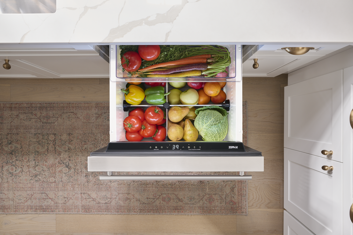 Under-counter stainless steel refrigerator drawer with fresh vegetables organized in a modern kitchen setting