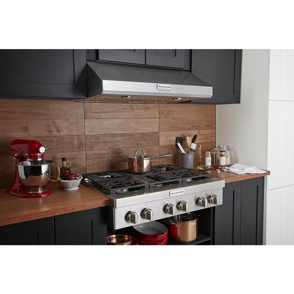 Modern kitchen setup featuring stainless steel 6-burner commercial-style gas rangetop with wooden backsplash and red mixer