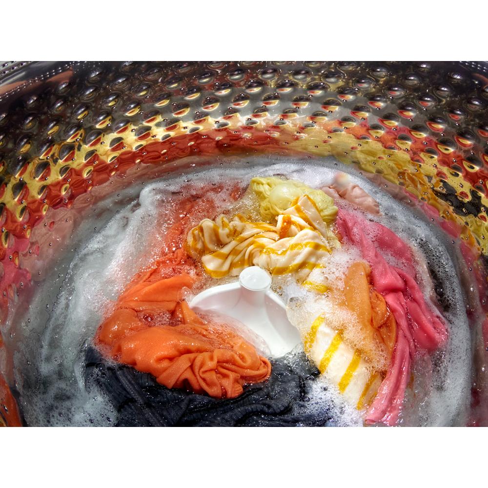 View inside a Whirlpool top load washer drum showing colorful clothes and soap suds in wash cycle