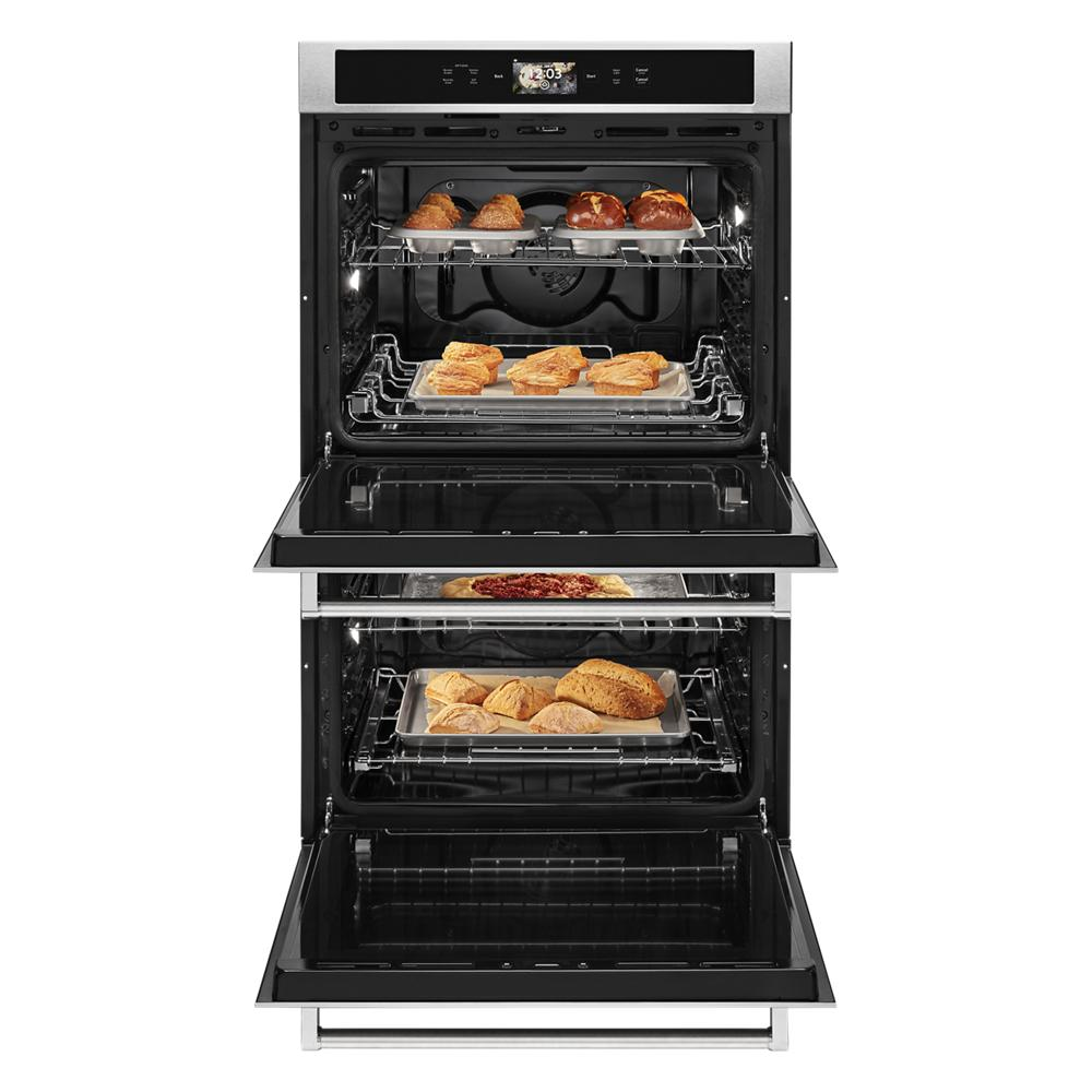 Open double wall oven with baked bread and pizza on stainless steel racks from KitchenAid appliances collection