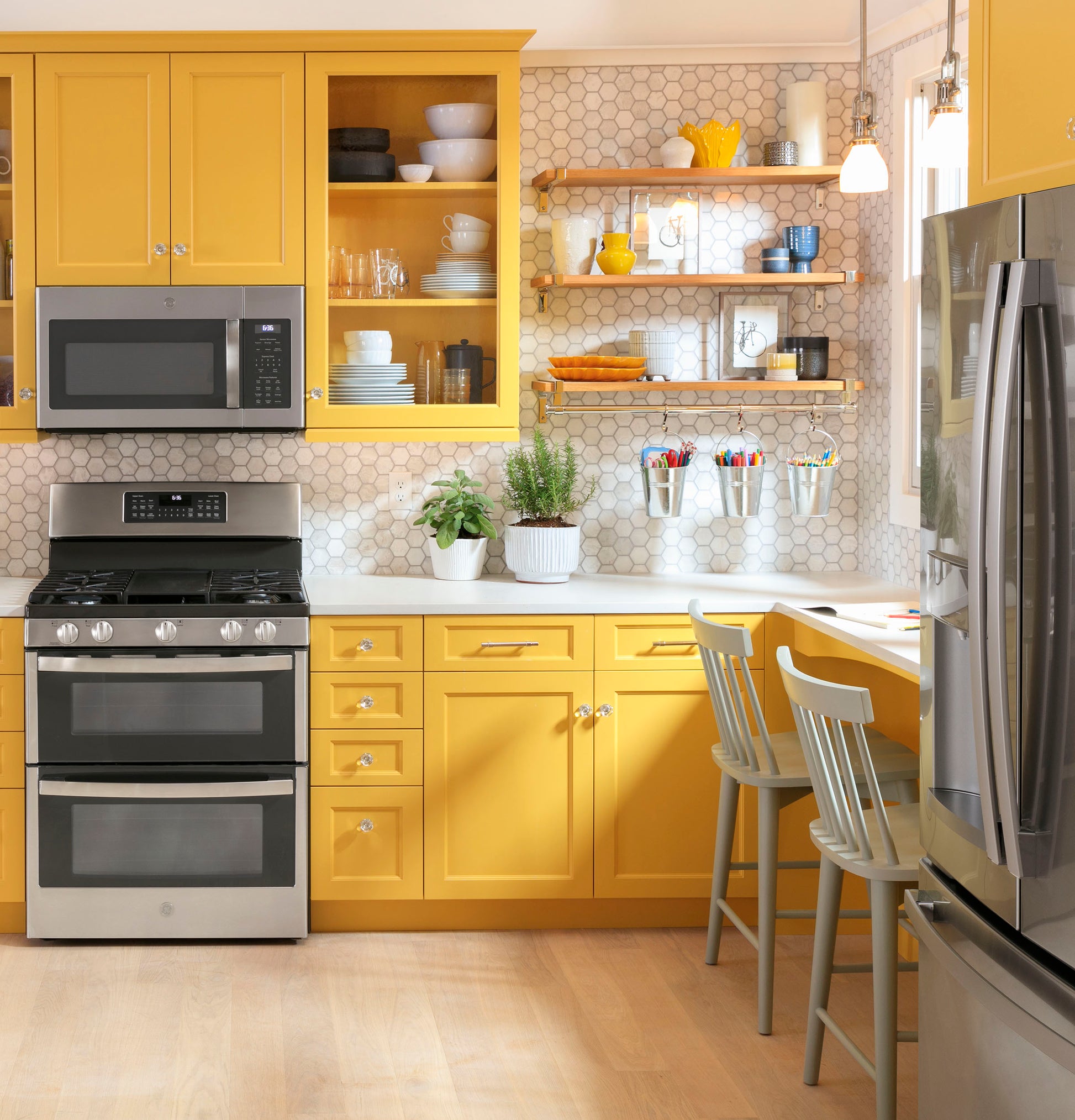 Over-the-range microwave with sensor controls installed above stainless steel range in bright kitchen with yellow cabinetry and hex tile backsplash
