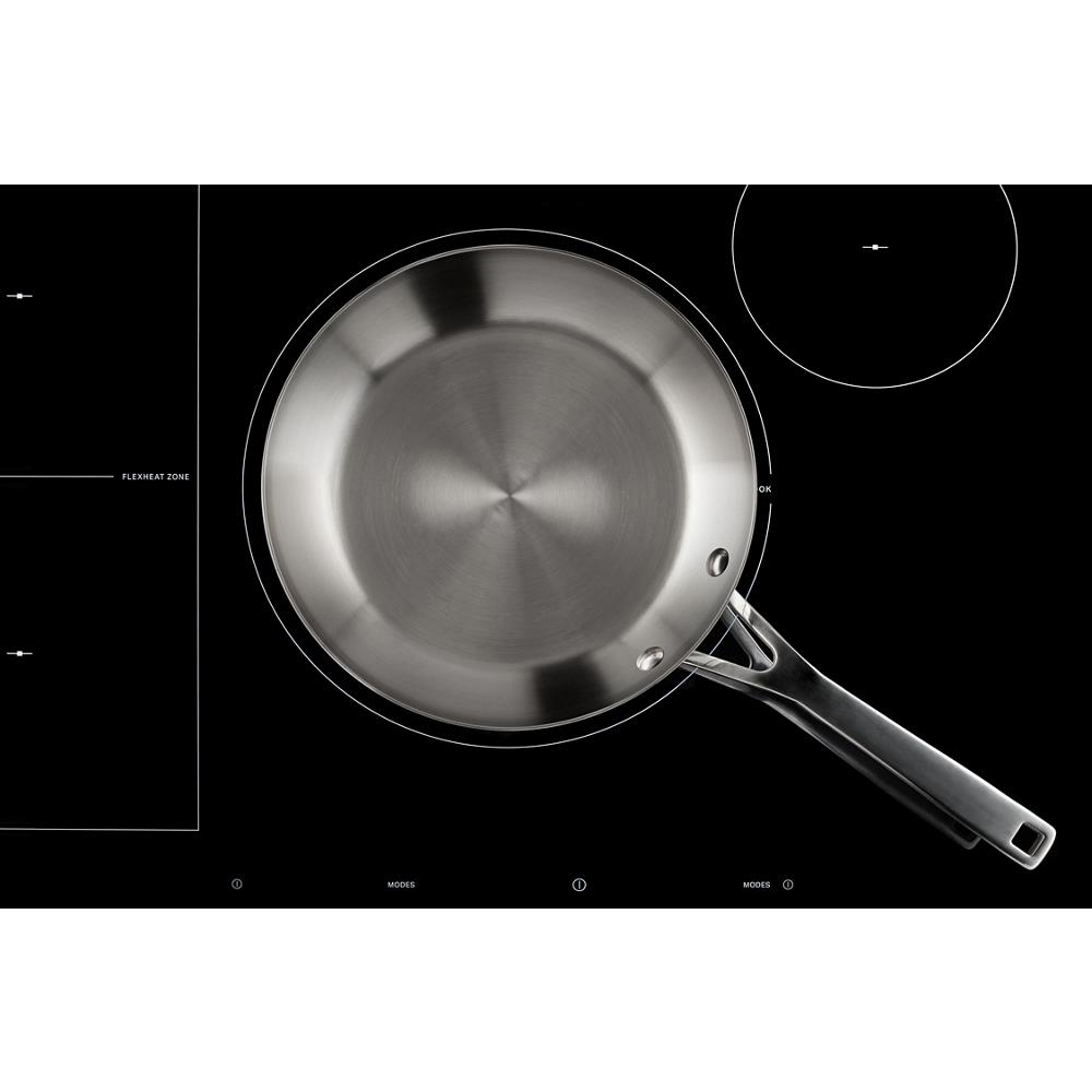 Black glass induction cooktop with flex heat zone and digital touch controls featuring a stainless steel frying pan