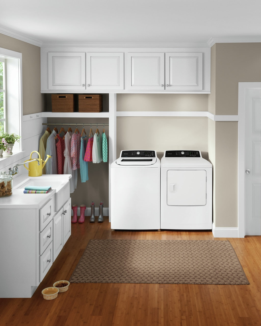 Laundry room featuring white large capacity dryer and washer with overhead cabinets and organized clothing rack nearby