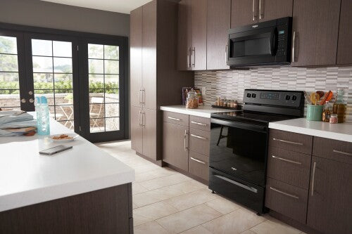Contemporary kitchen with dark wood cabinets featuring black over-the-range microwave and matching freestanding oven