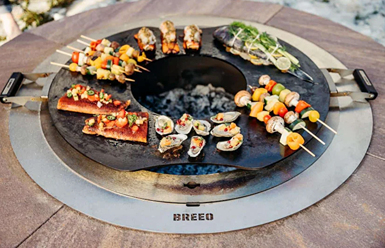 Hot-rolled carbon steel searplate griddle with handles cooking vegetables and seafood over fire pit for outdoor living collections