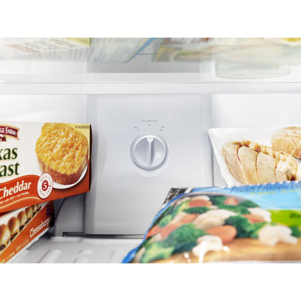 Freezer compartment temperature control dial inside a top freezer refrigerator with frozen food items visible
