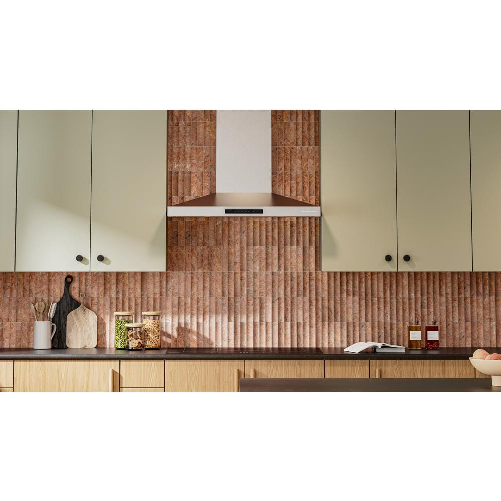 Stainless steel 36-inch wall-mount range hood with digital controls in kitchen with wood cabinets and textured backsplash