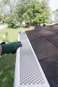 White vinyl snap-in gutter screen being installed on roof edge for home improvement debris protection