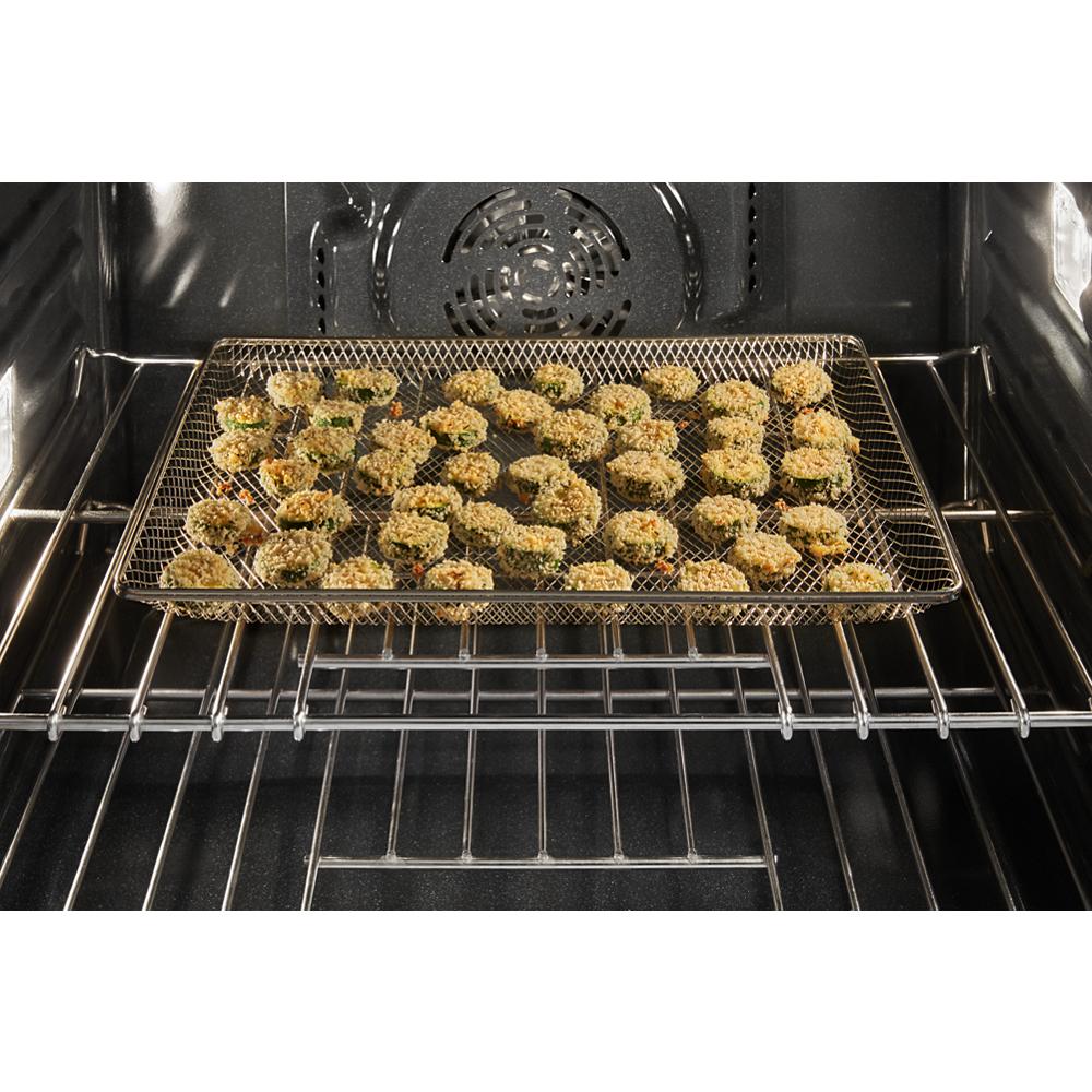Breaded food pieces arranged on a mesh basket inside a convection oven air fryer from a wall oven combo