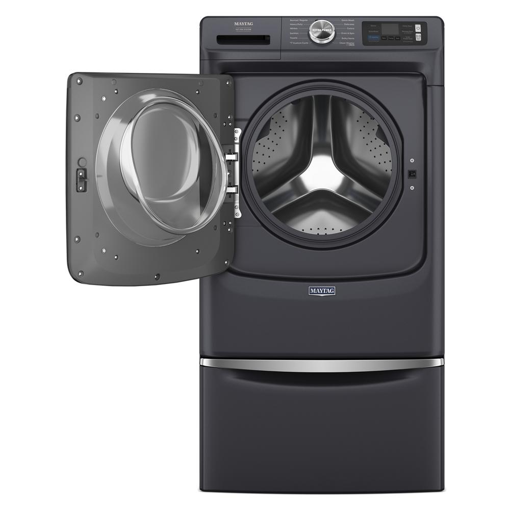Dark front load washing machine with open door showing stainless steel drum and matching pedestal drawer below