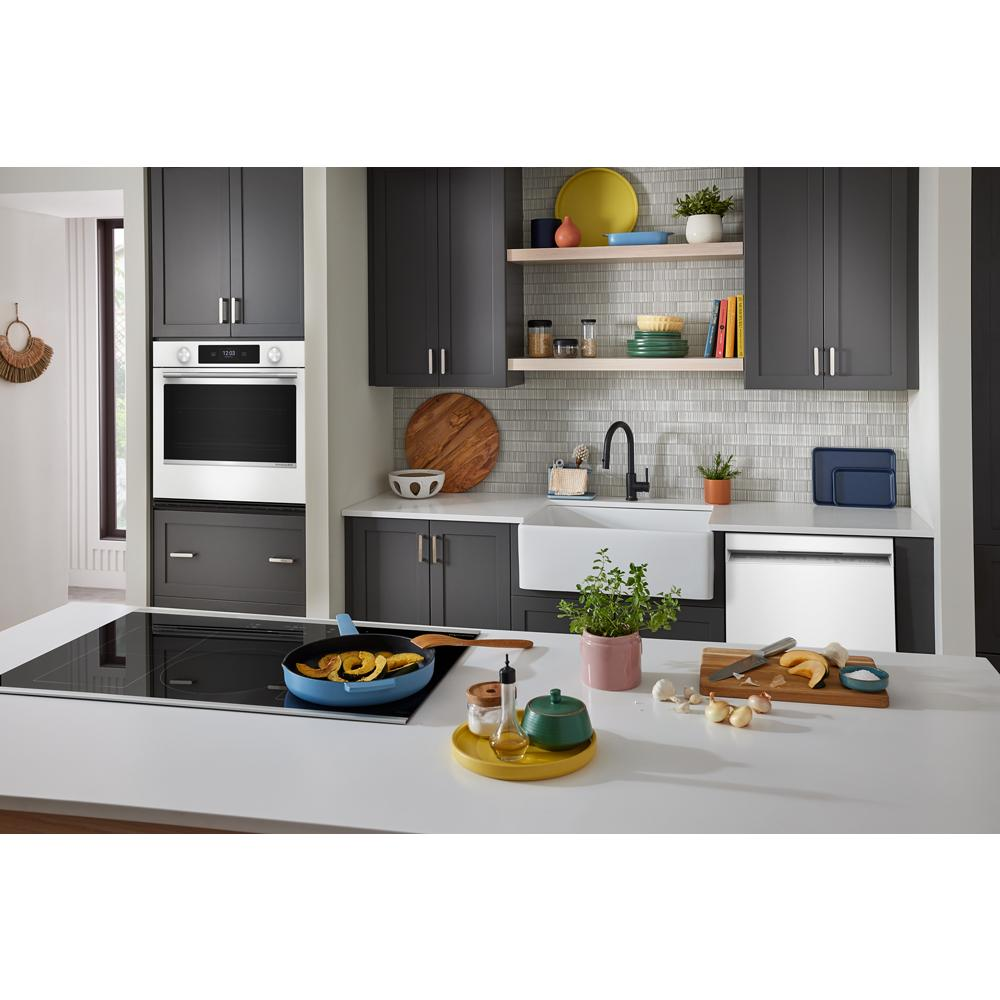 Modern white built-in 30-inch smart electric wall oven installed in dark gray kitchen cabinetry with countertop and sink nearby