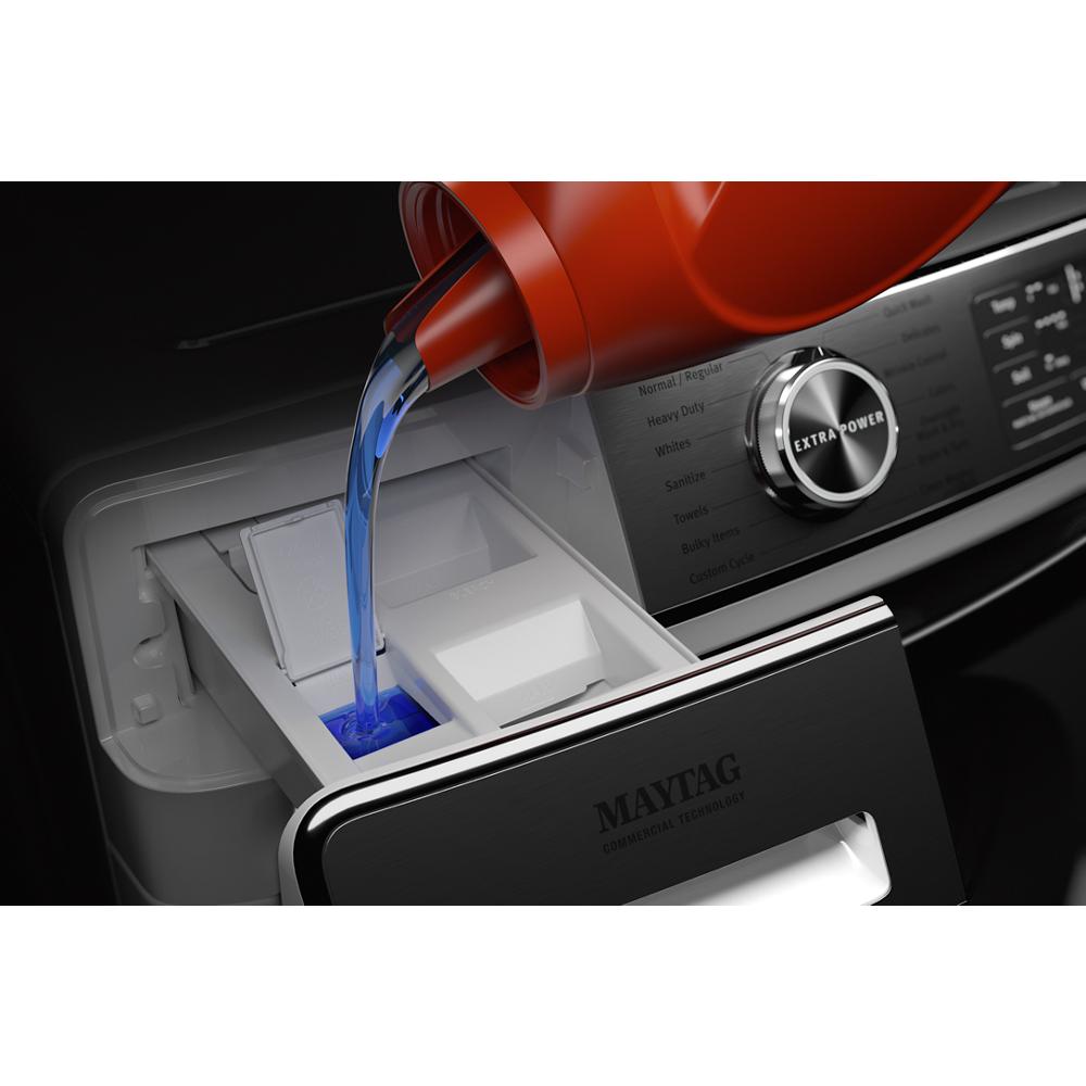 Pouring blue liquid detergent into the detergent compartment of a smart front load washer with extra power knob