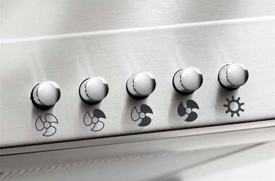 Close-up of stainless steel control panel with five round knobs featuring different fan speed and light icons, part of Range Hoods and Kitchen & Kitchenware collections for home improvement.