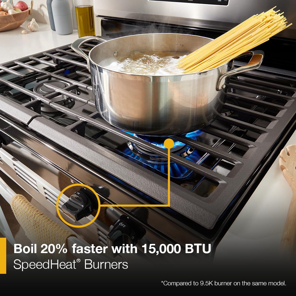 Stainless steel pot boiling pasta on high heat burner of a modern gas range in kitchen setting