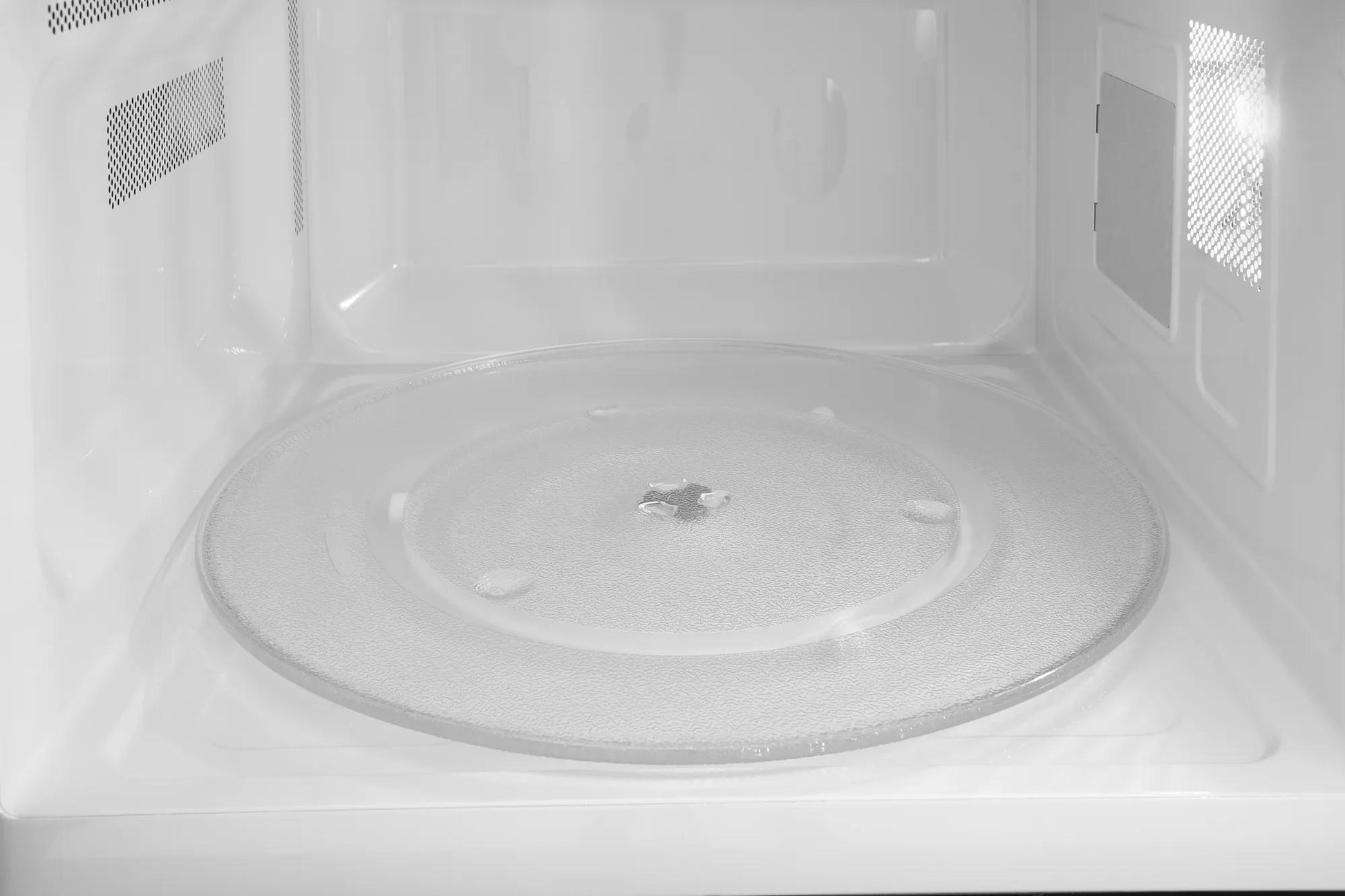 Interior view of built-in microwave featuring glass turntable and bright LED lighting for kitchen appliances use