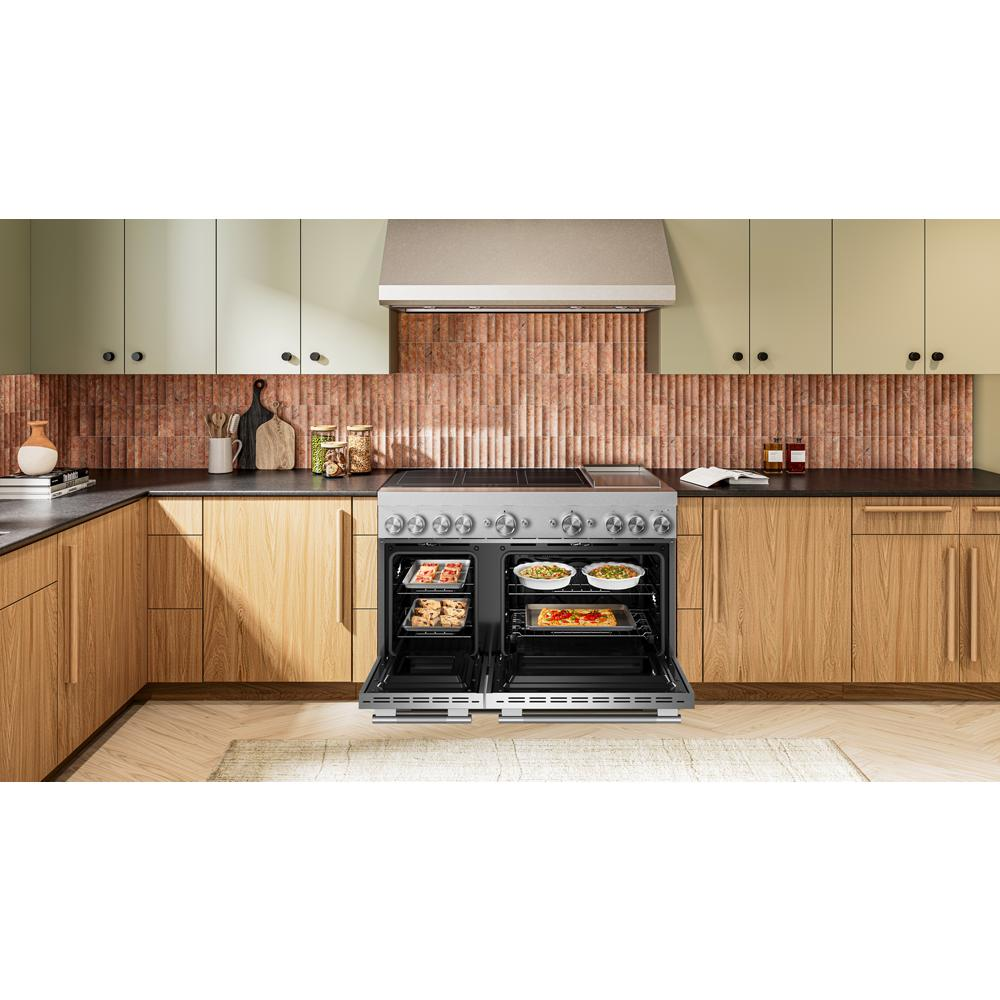 48-inch stainless steel commercial induction range with dual open ovens cooking multiple dishes in modern kitchen