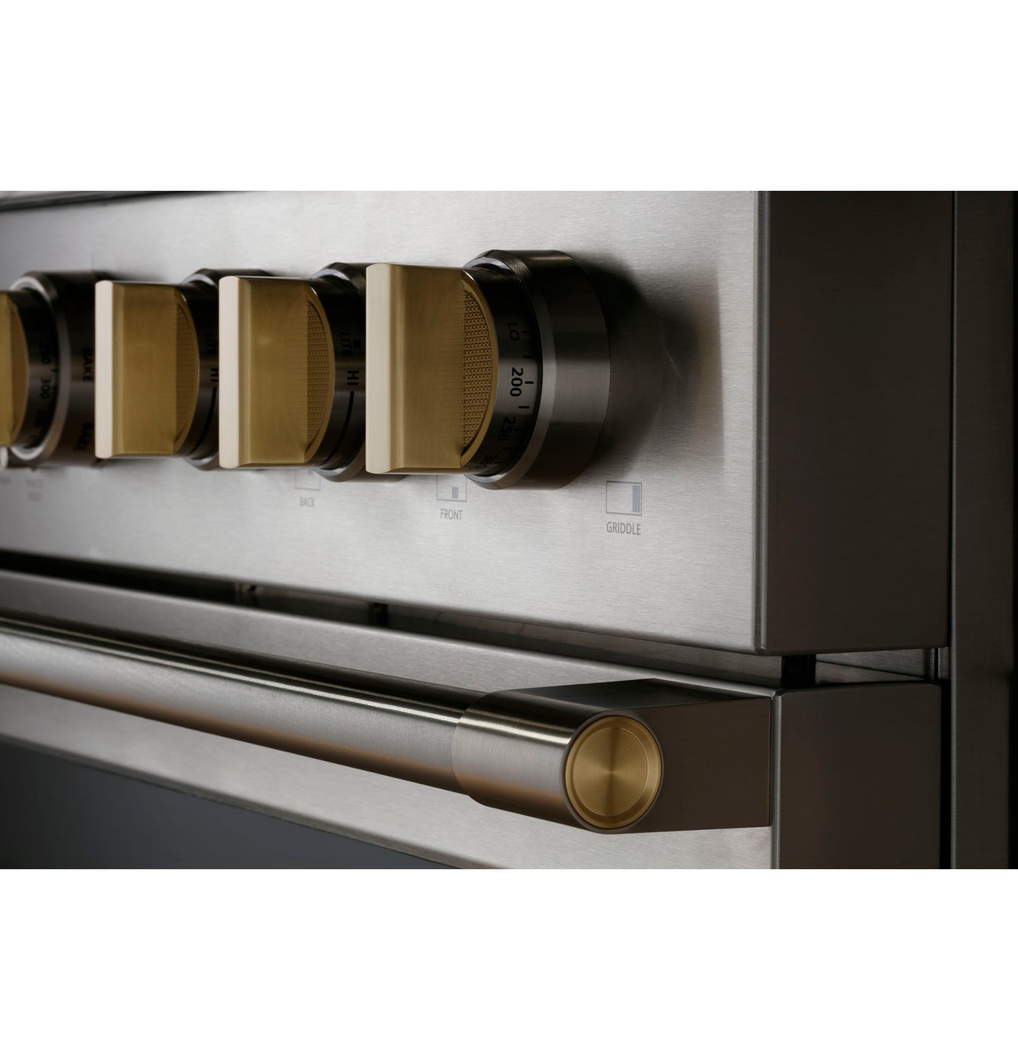 Close-up of stainless steel dual-fuel range control knobs and handle featuring brushed brass accents in kitchen appliances collection