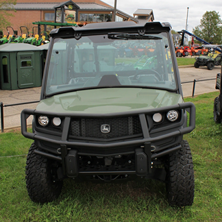 Front view of a green John Deere utility vehicle equipped with a sturdy black front brush guard and rugged tires.
