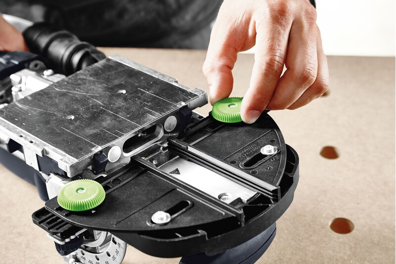 Close-up of a hand adjusting green knobs on a Festool Domino joiner tool accessory for woodworking precision