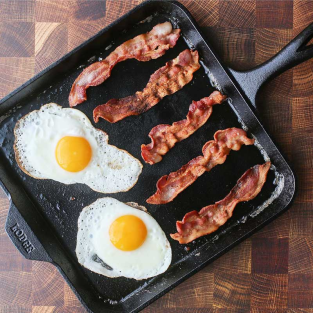 Cast iron 11-inch square griddle cooking sunny side up eggs and crispy bacon for kitchen and grilling use