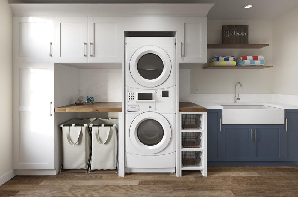 White electric stack washer and dryer combo in modern laundry room with storage and blue cabinetry