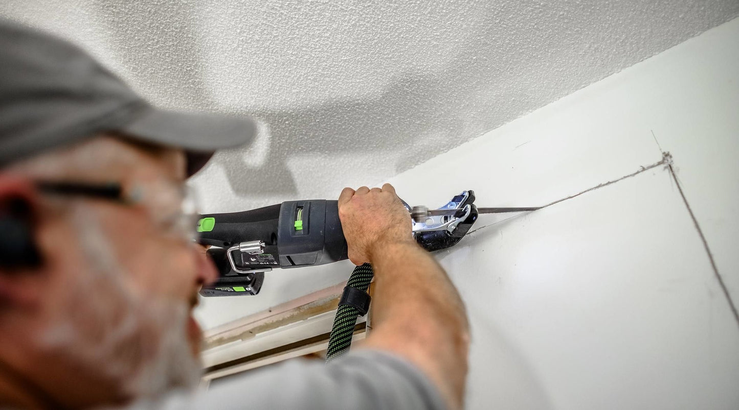 Man using Festool cordless reciprocating saw to cut drywall in home improvement and power tools setting