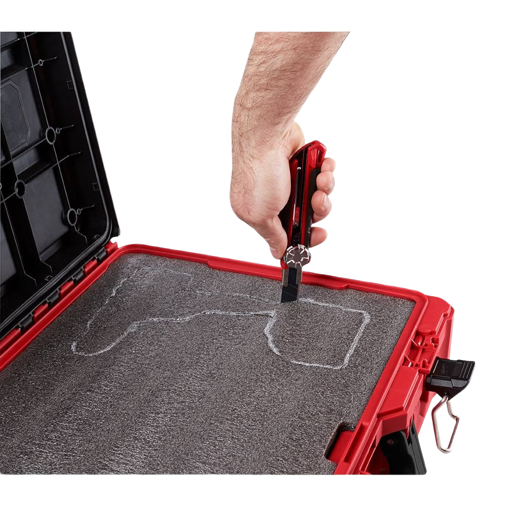 Hand trimming customizable foam insert inside a red Milwaukee PACKOUT™ tool case for organized tool storage