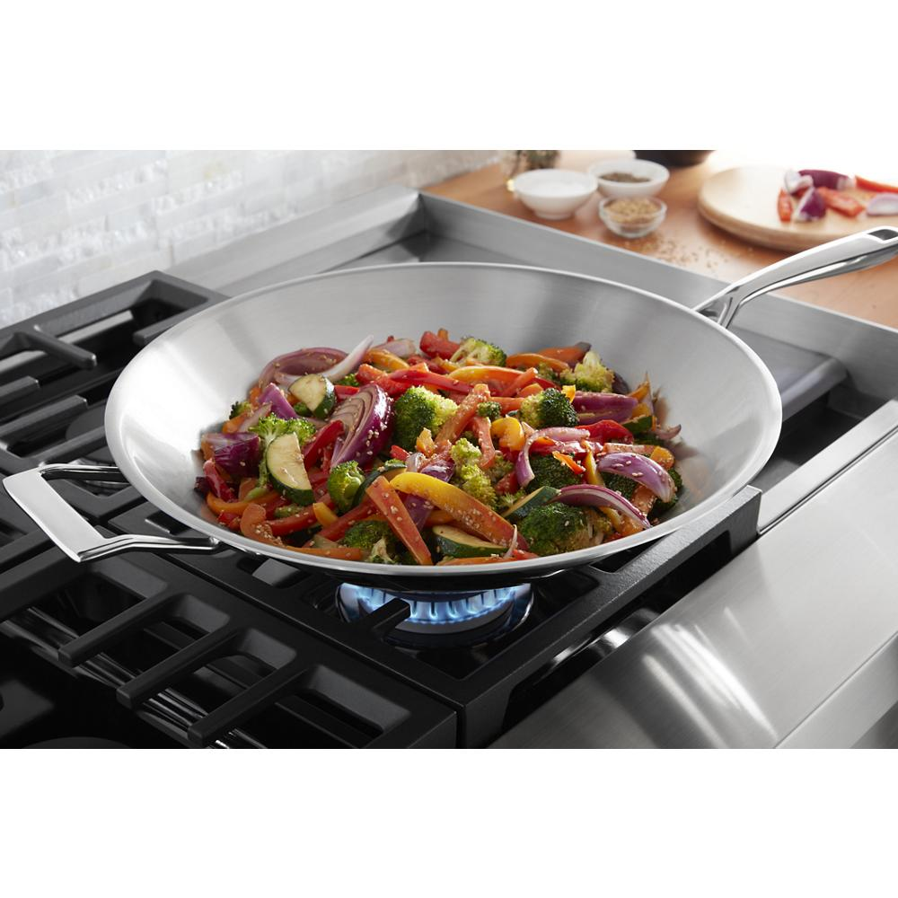 Stainless steel wok with colorful sautéed vegetables cooking on a modern gas burner in a KitchenAid range