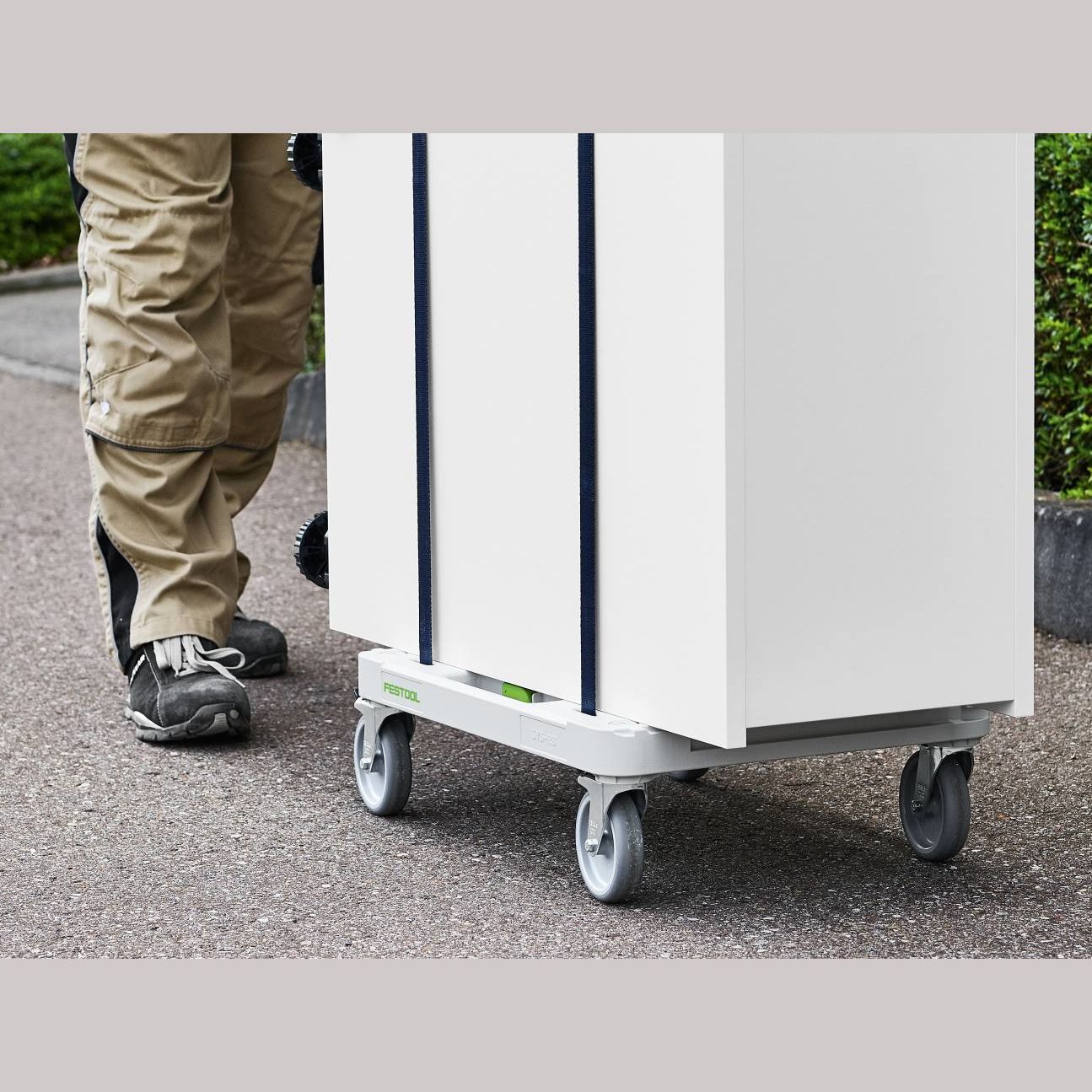 Person moving white storage cabinet on wheeled Festool SYS-Cart for workshop organization and tool storage solutions