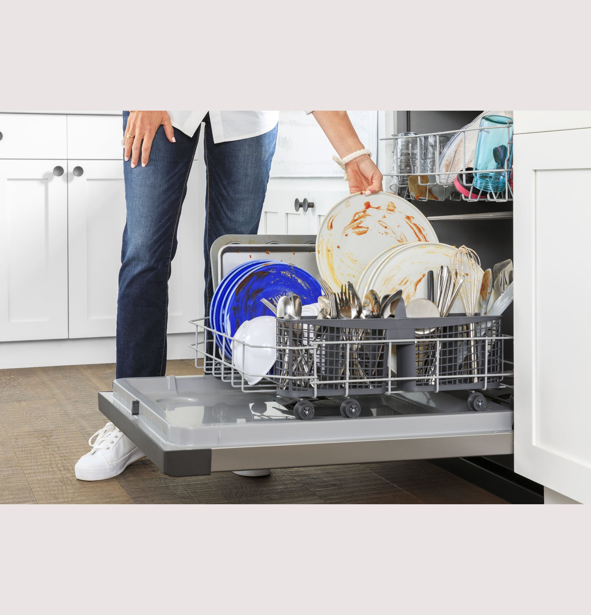 Person loading blue and white dishes into open GE ENERGY STAR dishwasher in modern kitchen setting