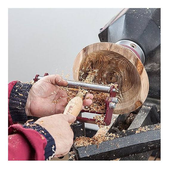 Woodturning bowl supported on steady rest with hands shaping wood using a chisel for home improvement tools use