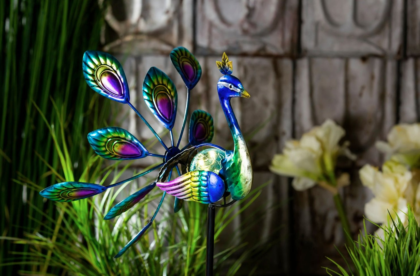 Decorative garden wind spinner shaped like a colorful peacock with vibrant tail feathers on a metal stake