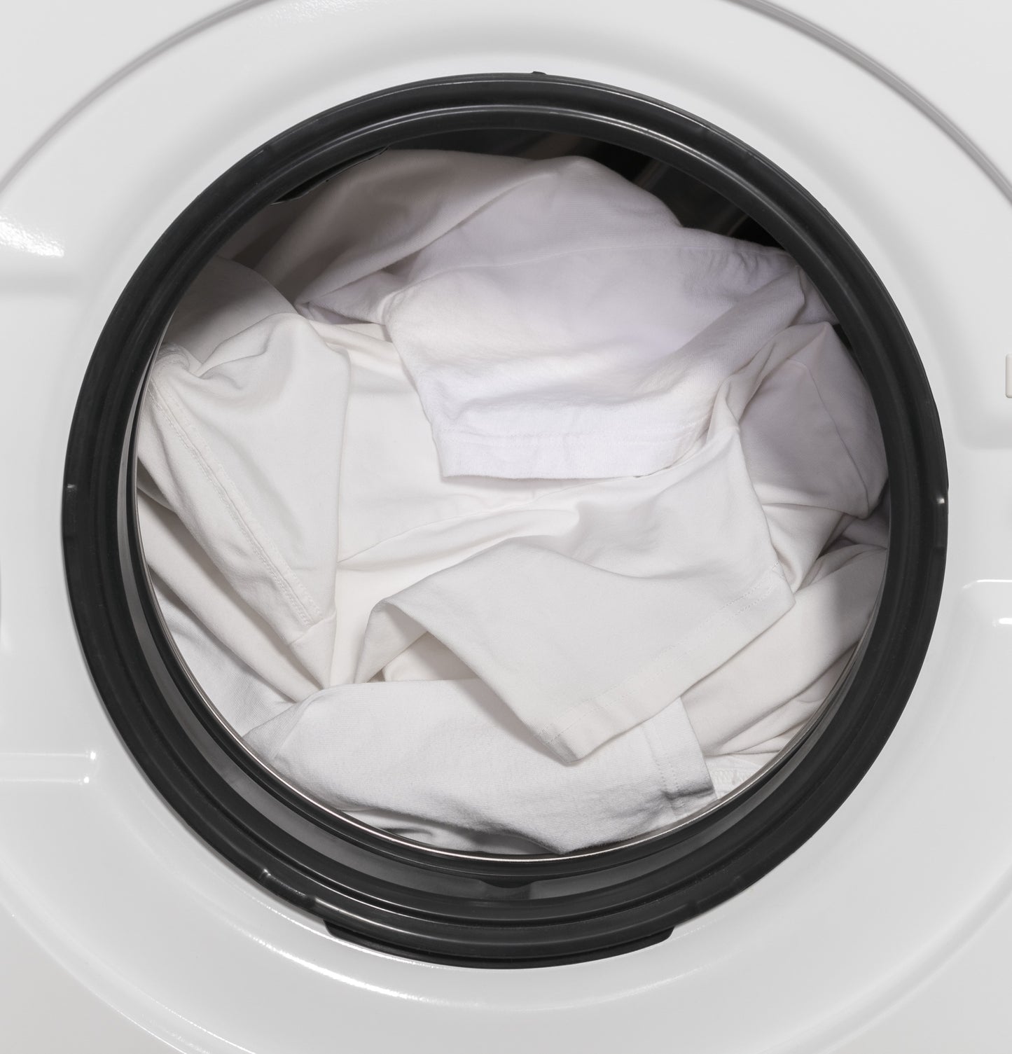 White clothes inside the front load washer door from the Washer/Dryer Combos collection in Appliances category