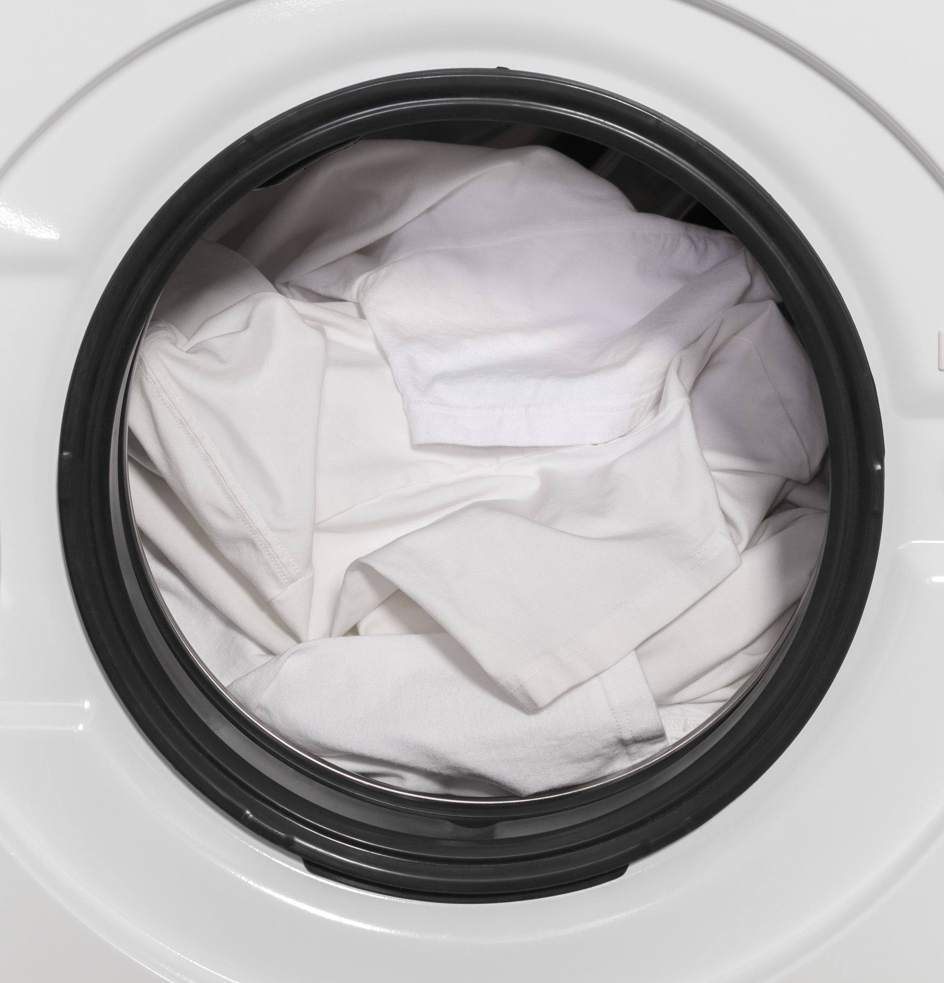 White clothes inside the front load washer door from the Washer/Dryer Combos collection in Appliances category