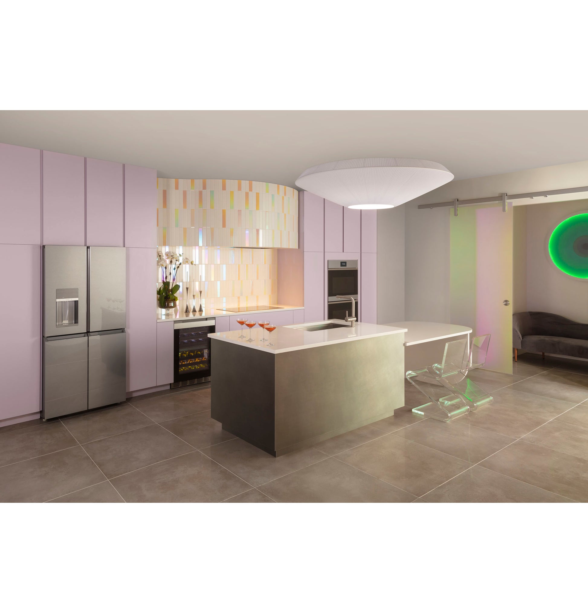 Modern kitchen with lavender cabinetry, stainless steel appliances, sleek island, and colorful tiled backsplash under ambient lighting