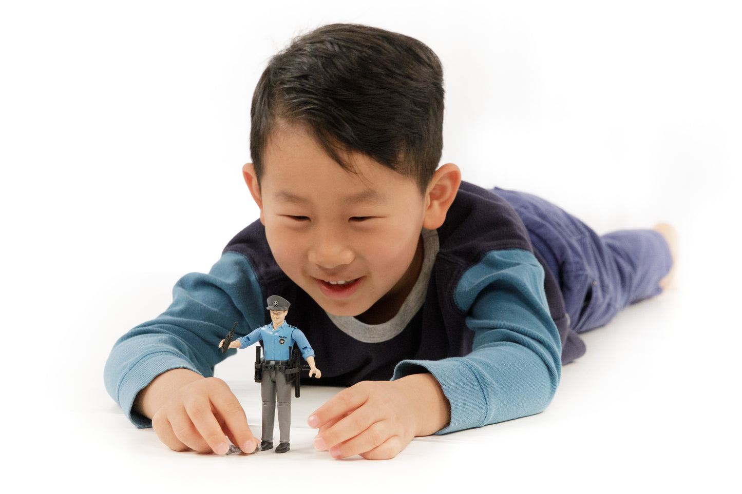 Child playing with a light skin policeman action figure dressed in blue shirt and gray pants with accessories