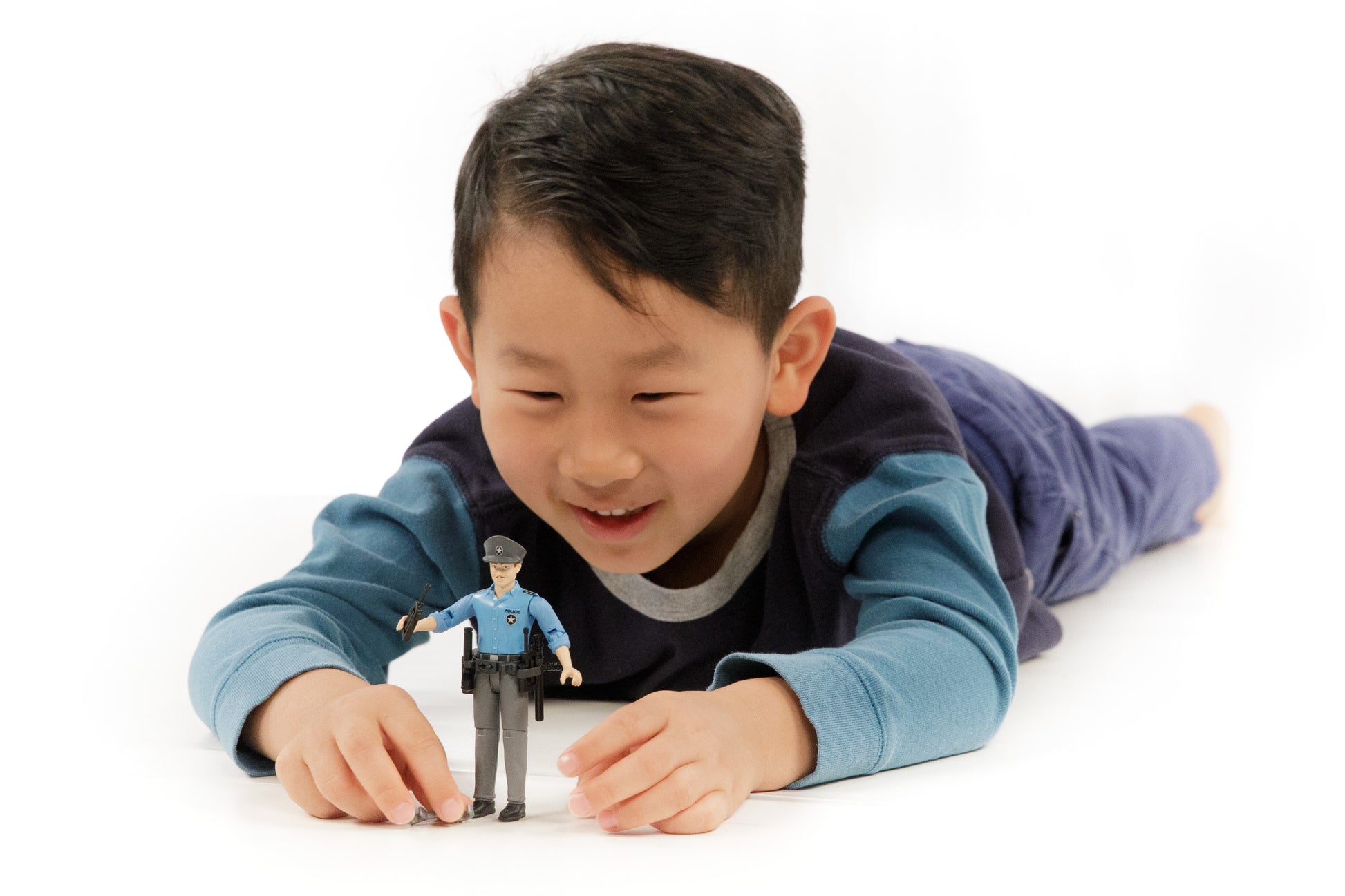 Child playing with a light skin policeman action figure dressed in blue shirt and gray pants with accessories