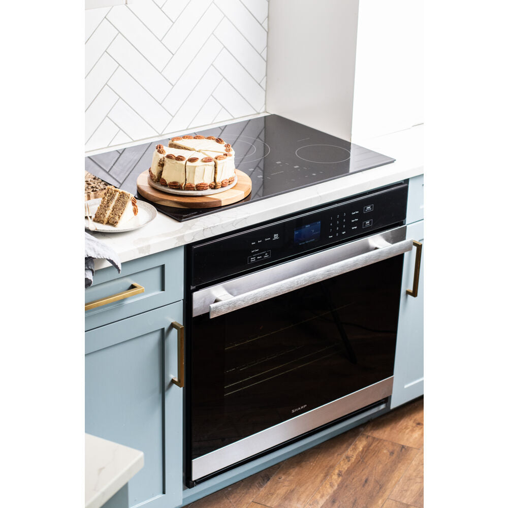 Built-in electric single wall oven with edge-to-edge black glass and stainless steel handle in modern kitchen setting
