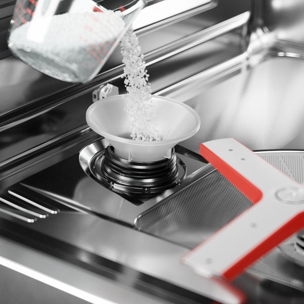 Close-up of white dishwasher salt pouring into a funnel inside a stainless steel Bosch dishwasher tub from Kitchen & Kitchenware collection