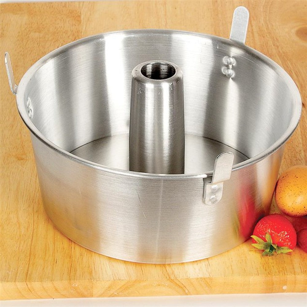 Round aluminum loose bottom angel food pan with center tube and locking clips on wooden surface near fruit