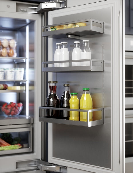 Open stainless steel refrigerator door with organized door racks holding bottles of milk, juice, and condiments in kitchen appliance collection