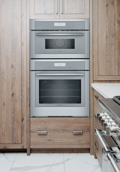 Built-in stainless steel combination wall oven and microwave integrated into modern wood cabinetry in kitchen improvement setting