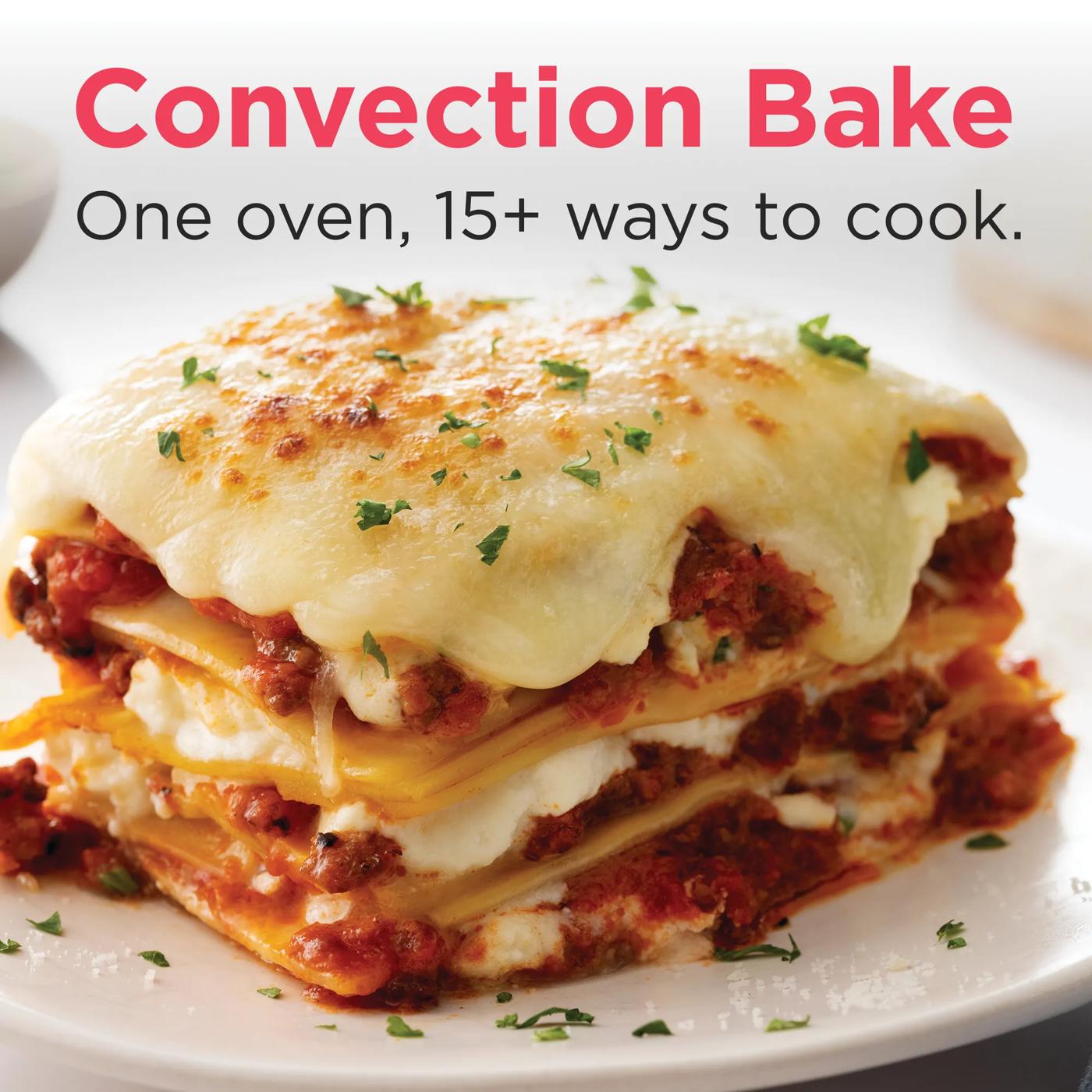 Close-up of a slice of cheesy baked lasagna with herbs, showcasing convection baking results from wall oven appliances